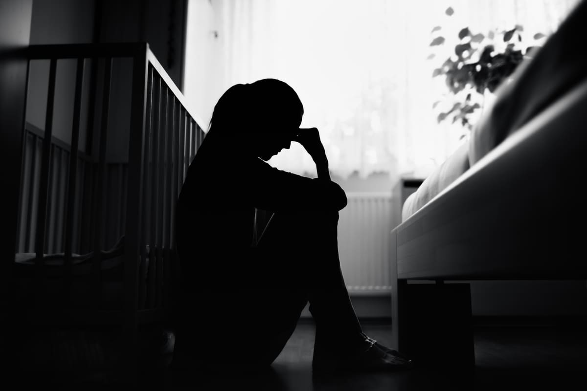 donna depressa vicina alla culla di un neonato