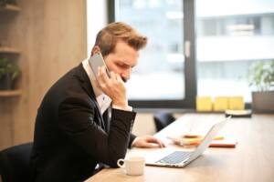 Uomo al telefono con computer e caffè