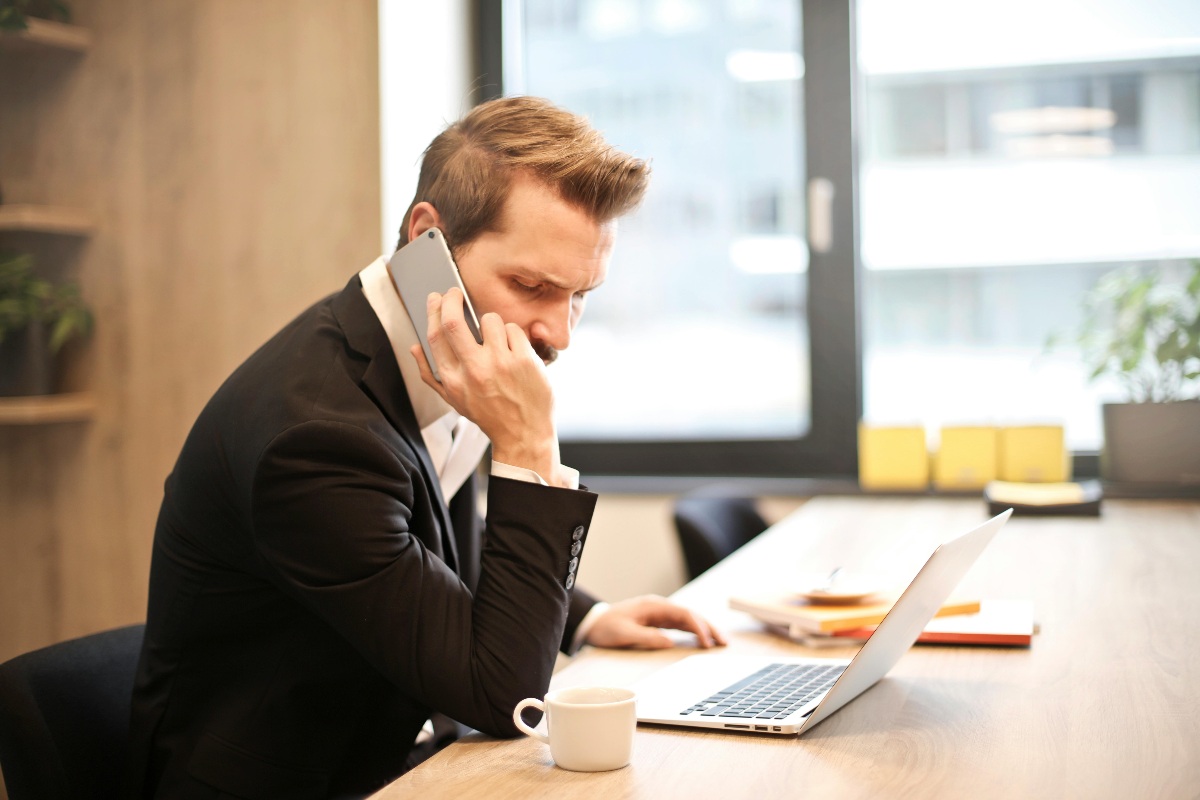 Uomo al telefono con computer e caffè