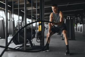 Ragazzo si allena intensamente con le funi in palestra.