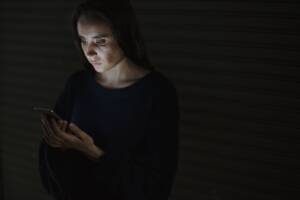 una donna usa un cellulare nell'ombra