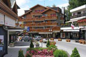 Veduta di una piazza di Crans-Montana, in Svizzera, caratterizzata da resort e tipica architettura alpina.