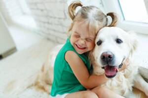 Una bambina che stringe in un grande abbraccio un Golden Retriever.