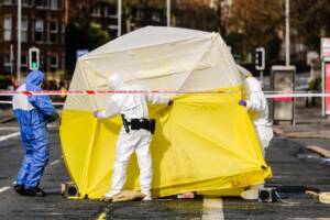 agenti della scientifica con una tenda sulla scena del crimine