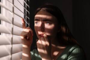 una ragazza osserva spaventata fuori dalla finestra